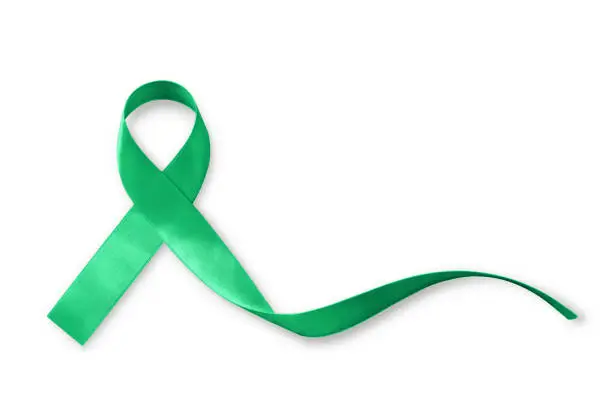 Photo of Green ribbon awareness symbolic bow for Kidney, Gallbladder, Bile Duct Cancer, Glaucoma, Leukemia, Traumatic Brain Injury, and Mental Health illness (bow isolated on white with clipping path)