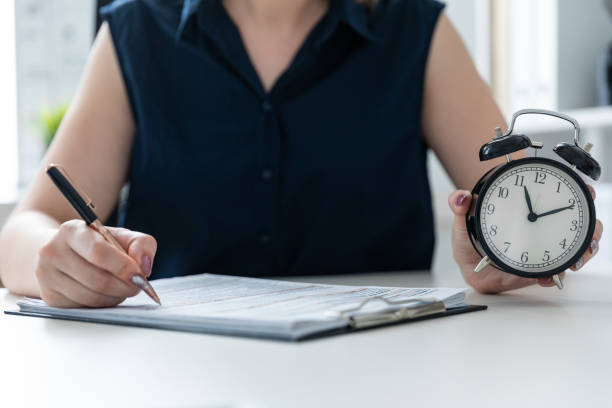 istock Women's hands holding a pen and an alarm clock. 1093761836