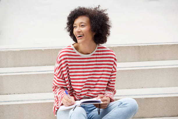istock happy woman sitting on steps with book and pen 1093765542