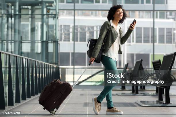 Full Body Side Of Travel Woman Walking At Station With Suitcase And Cellphone Stock Photo - Download Image Now