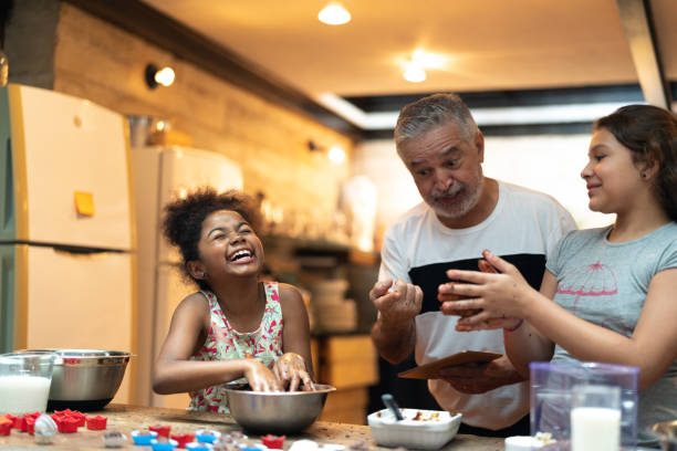 hispanic-latino großvater lehrt ihr enkelkind wie zu hause - kochen sie bereiten brasilianischen brigadeiro - family domestic life senior adult computer stock-fotos und bilder