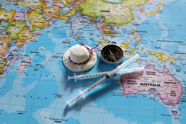 A compass with two disposable syringes and travel cap on world map. stock photo