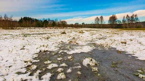 Winter meadows with snow and frozen puddle. Beautiful polish landscape.