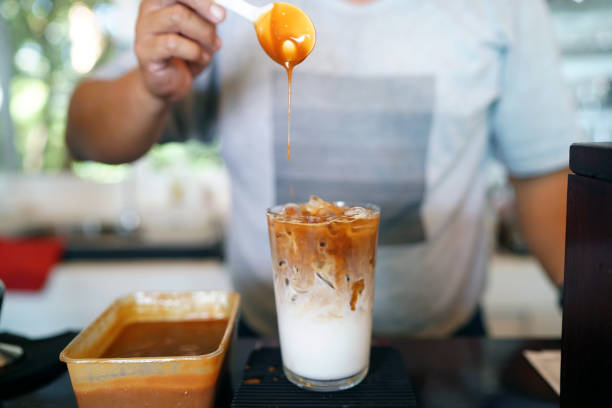 iced caramel macchiato - a glass of espresso mixed with vanilla syrup, milk and ice, topping with caramel syrup, refreshing homemade summer drink concept. - caramel latté coffee cafe macchiato imagens e fotografias de stock