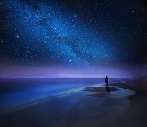 istock Starry night sky over sea and beach with man silhouette 1093831732