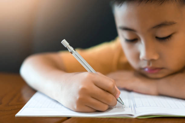 kleine junge hand schreibt hausaufgaben zu hause. bildungskonzept - reading and writing little boys reading asian ethnicity stock-fotos und bilder