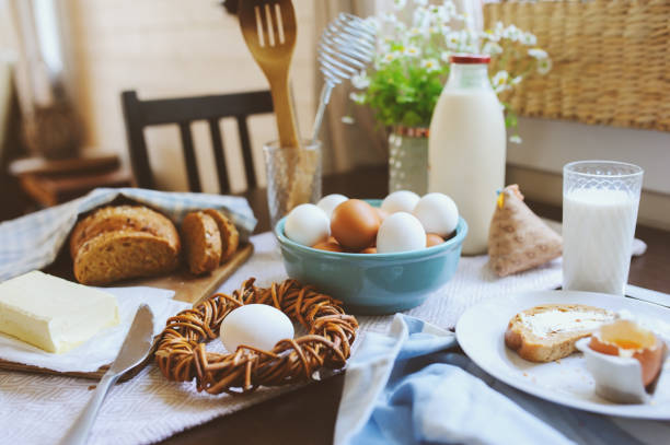 country breakfast on rustic home kitchen with farm eggs, butter, wholegrain bread and milk. Organic homemade food, easter concept.