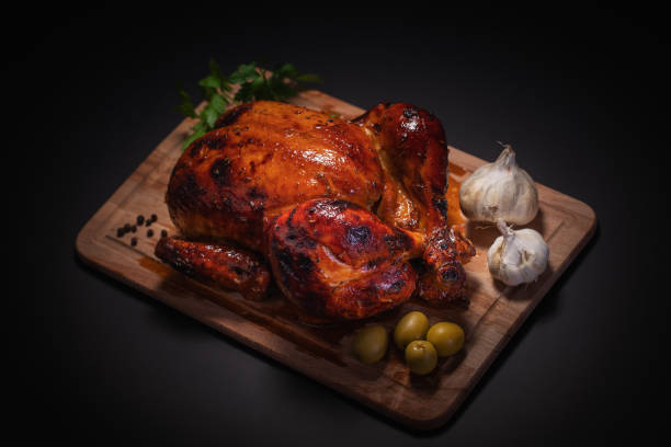istock Whole roasted chicken on cutting board with vegetables over black background 1093857434
