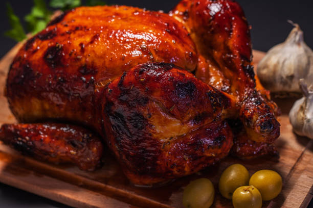 istock Whole roasted chicken on cutting board with vegetables over black background 1093857468