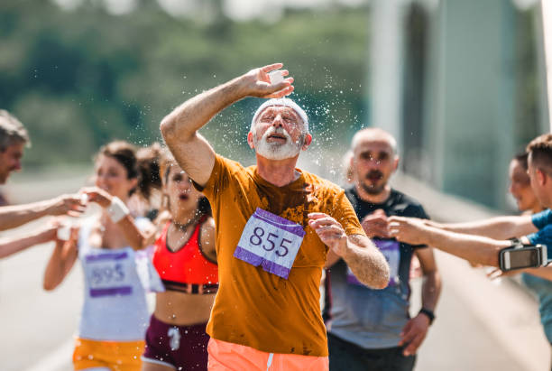 istock Exhausted mature runner pouring fresh water on his head during a marathon race. 1093869926