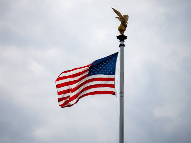 istock American flag blowing on overcast day with eagle statue over head 1093883740
