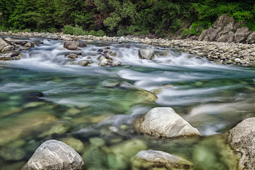 The photo was taken with a very strong ND-Filter to make possible an exposure time from about 4 seconds at daytime. Flowing water in a riverbed in the Swiss Alps. Exactly it is river Maggie in the Valle Verzasca in Switzerland.