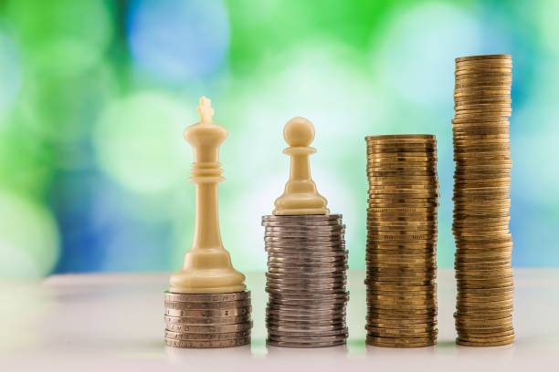 istock Growing coins stacks with green and blue sparkling bokeh background. Chess figures standing on coins meaning power and career growth. Financial growth, saving money, business finance wealth and success concept. 1093888536