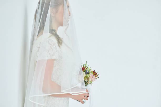 Full length profile shot of a bride with a veil isolated on white background
