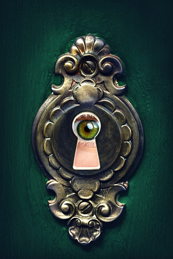 Female eye looking through a keyhole