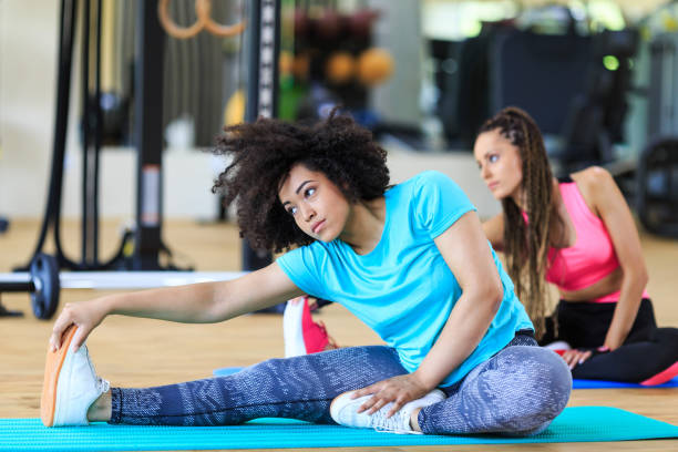 istock Women sitting on ground and stretching in gym 1093895982