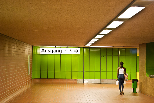 A female commuter walking towards the exit (Ausgang in German) at a train station in Dortmund, Germany