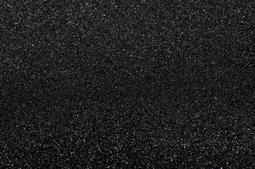 The texture of black stone (minerals) crumb. Black abstract background with defocused area. Top view.