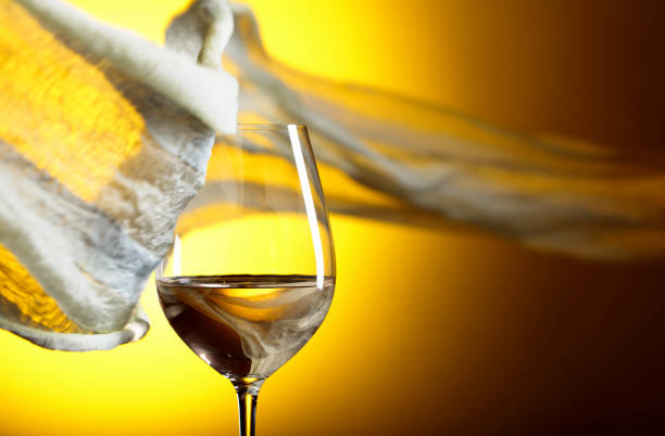 Close-up of pouring white wine into the wine glass, directly above. Studio shot, white background.