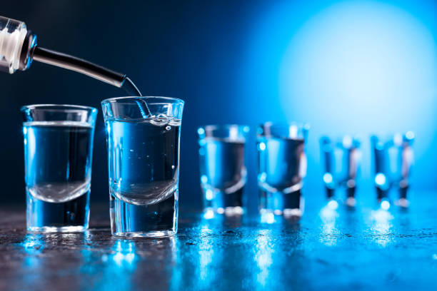 vodka poured into a glass lit with blue backlight. - russian shot imagens e fotografias de stock