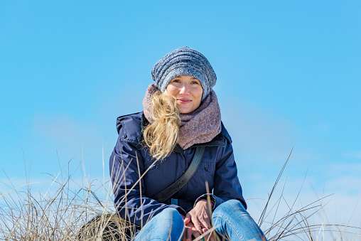 Beautiful woman sits in the sun on a dune