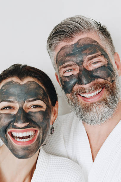 pareja feliz con una máscara de carbón - spa treatment health spa couple happiness fotografías e imágenes de stock