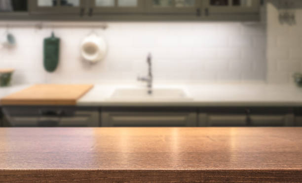 Wooden table top on kitchen island in front of blurred home interior. stock photo