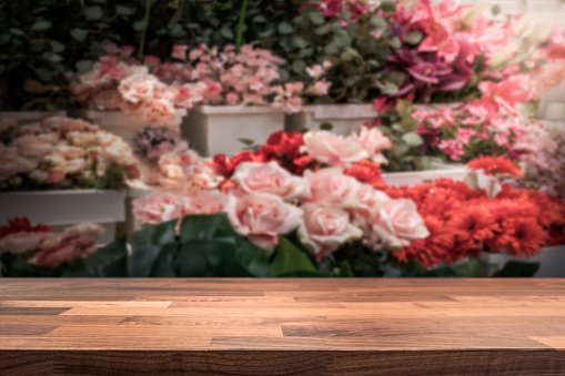 Wooden table top / shop counter in front of blurred flower store. Background for product display montage. Copy space design.