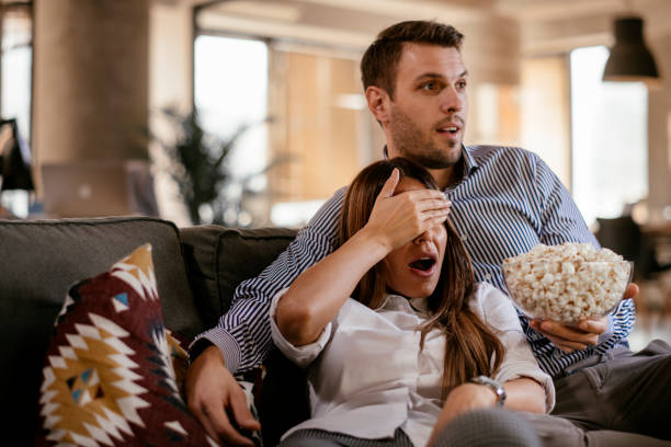 istock Young couple with popcorn looking horror movie 1093923068