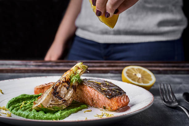istock hand squeezes lemon over Baked salmon steak with mashed green peas , caramelized onions. 1093928934