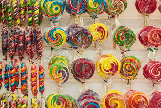 Rows of colorful spiral and rainbow-swirl lollipops on display on the shelves in the market,