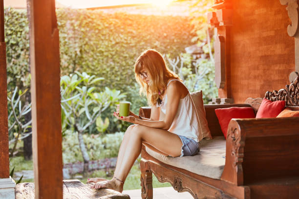 istock Cute woman using drinking tea on a porch sofa. 1093935132
