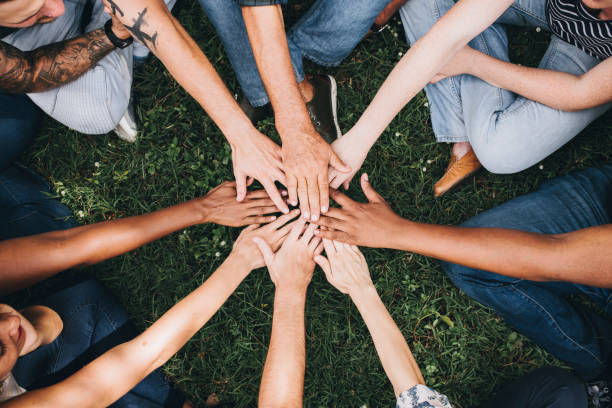 people stacking hands together in the park - community teamwork human hand organization imagens e fotografias de stock