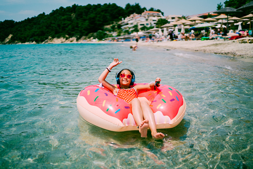 Relaxed girl in life belt floating on water with good music