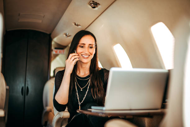 istock Beautiful rich woman working on a laptop and talking on a smart phone at the same time while flying on a private jet 1093943886