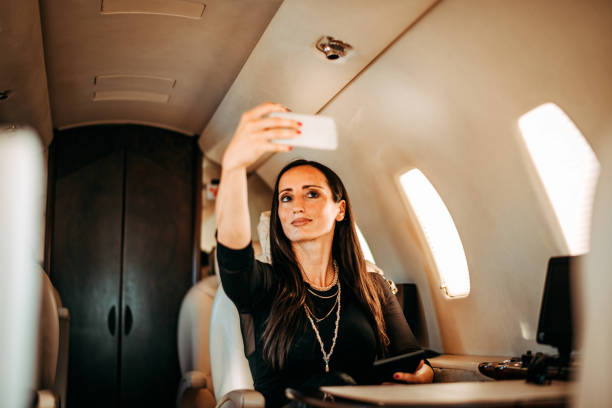 istock Rich woman using a mobile phone to take a selfie while traveling on a private jet 1093943900
