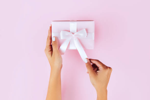istock Woman hands holding present box with pink bow on pastel pink background. 1093952872