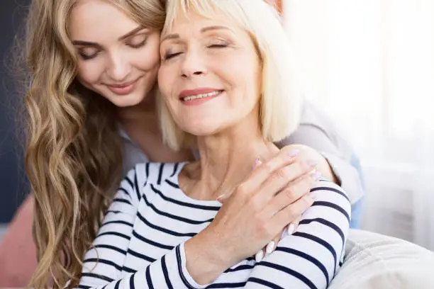 Photo of Cute young daughter embracing her mother with love