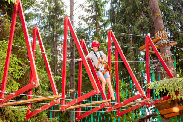 teen boy sur un parcours d’accrobranche en hauteur dans un passage de parc aventure treetop suspendus obstacle de corde - high up obstacle course ropes course teenage boys photos et images de collection