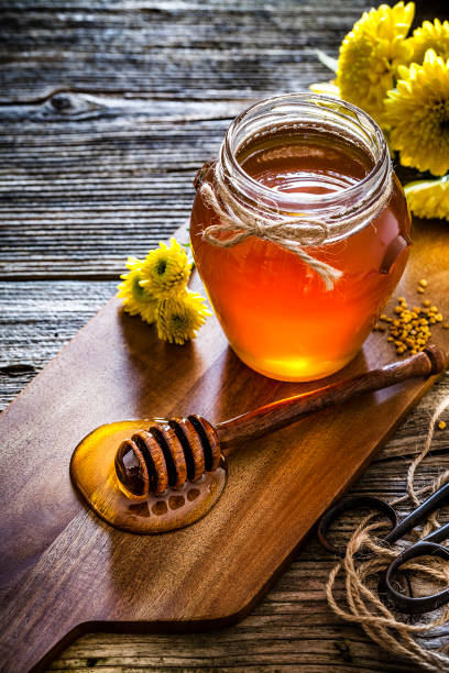 Honey jar with honey dipper shot on rustic wooden table