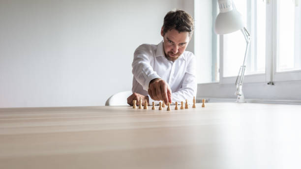 istock Young business executive positioning white chess pieces in a sensible structure 1093968474