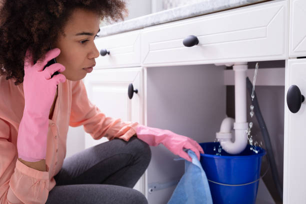 istock Woman Calling Plumber In Front Of Leaking From Sink Pipe 1093971960