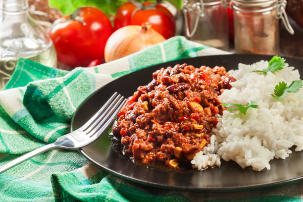 Hot chili con carne with ground beef, beans, tomatoes and corn served with rice stock photo