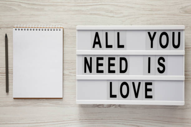 istock Modern board with text 'All you need is love', notepad with pencil over white wooden background, top view. From above, flat lay, overhead. 1093975870