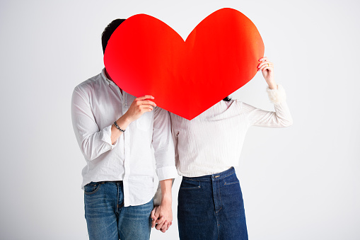 Happy young couple is holding red paper hearts,love story Valentine's Day