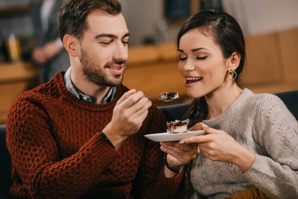 istock handsome man feeding attractive woman with cake in cafe 1093984728