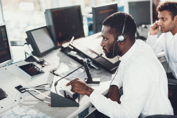 Dispatcher speaking by microphone on navigation board Center of dispatching maintenance. Top angle side on portrait of afro-american male specialist speaking on microphone while working on navigation control board dispatcher stock pictures, royalty-free photos & images