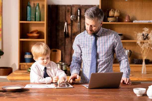 ładny chłopiec w białej koszuli omawiający interesy z ojcem w kitch - ipad baby boys little boys caucasian zdjęcia i obrazy z banku zdjęć