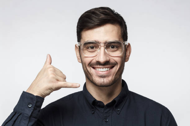 istock Young man showing gesture as if asking to calll him, looking confident, isolated on gray background. Technical support concept 1093992024
