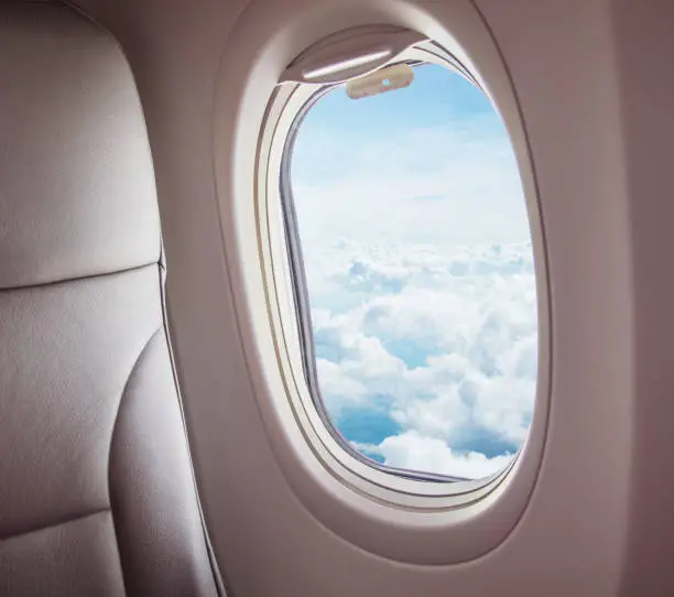 Airplane interior with window view of clouds. Concept of travel and air transportation